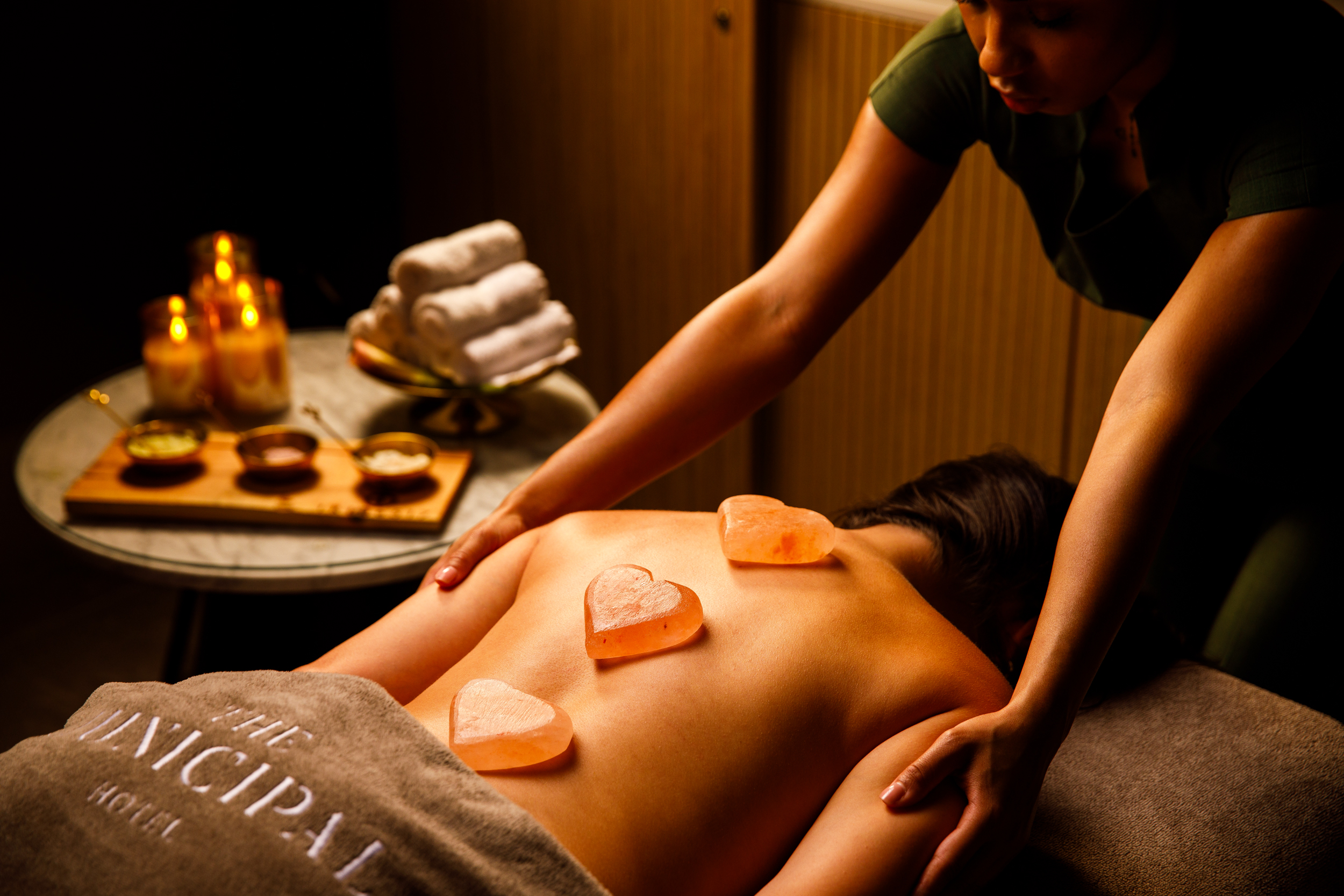 Guest being stretched on a treatment bed beside hot stones